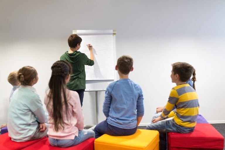 student boy with marker writing on flip board